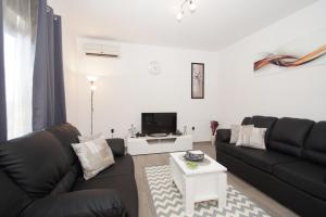 ein Wohnzimmer mit einem schwarzen Sofa und einem weißen Tisch in der Unterkunft Family friendly house with a swimming pool Brna, Korcula - 13943 in Smokvica