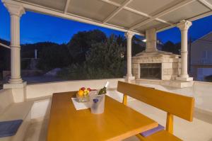 a wooden table and bench on a porch with a fireplace at Family friendly house with a swimming pool Brna, Korcula - 13943 in Smokvica