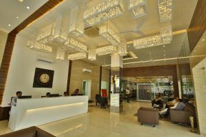 a lobby with people sitting in chairs and a clock on the ceiling at Jhansi Hotel in Jhānsi