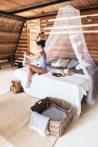 a woman sitting on a bed in a room at Azul Nomeolvides in Bacalar