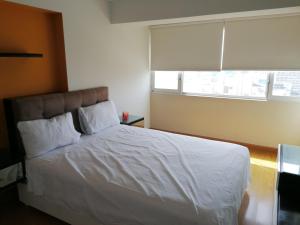 a bedroom with a bed with white sheets and a window at Apart Peru II in Lima