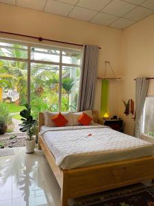 a bedroom with a large bed and a large window at BinhYen Homestay in Mui Ne