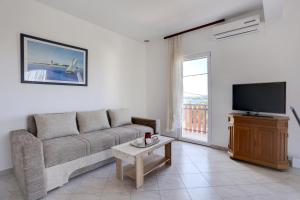 a living room with a couch and a television at Family friendly apartments with a swimming pool Kastel Sucurac, Kastela - 14047 in Kaštela