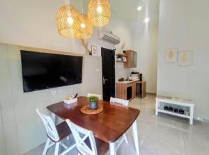a dining room with a table and chairs and a television at Cottonwood Boutique Heritage Otten in Bandung