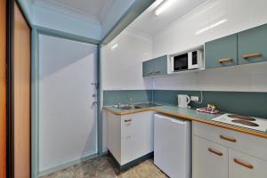 a kitchen with a sink and a microwave at Oscar Motel in Bundaberg