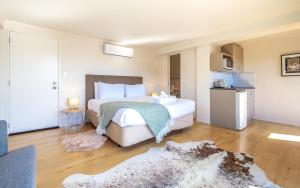 a bedroom with a large white bed and a kitchen at Aqua Sands #1 in Oneroa