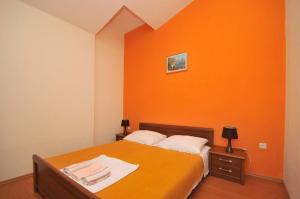 sypialnia z pomarańczową ścianą i łóżkiem w obiekcie Apartments with a parking space Okrug Donji, Ciovo - 13732 w mieście Okrug Donji