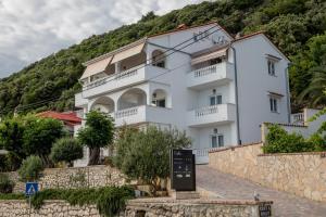a white building with balconies on a hill at Double Room Supetarska Draga - Gornja 11579a in Rab