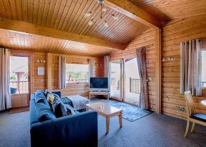 a living room with a blue couch and a tv at Fingle Glen Lodges in Whitestone