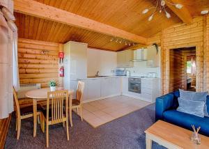 a kitchen and dining room with a table and a blue couch at Fingle Glen Lodges in Whitestone
