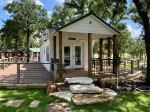 a small white building with a porch and some rocks at Farmhouse Style Tiny Home with Patio - 4 mi to Town in Fredericksburg