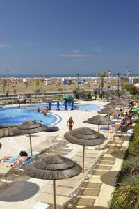a pool with umbrellas and people at the beach at Ashanti Aparthotel Wellness&Spa in Bibione