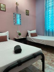 Seri Idaman Guest House (Pasir Mas) في Kampong Taman: غرفة بسريرين وقبعة على السرير