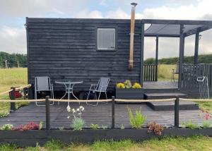 a small cabin with a table and chairs on a deck at Glamp At The Priory in Aldeby