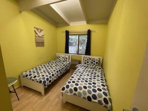 two beds in a room with yellow walls at Family Beach Home Dromana in Dromana