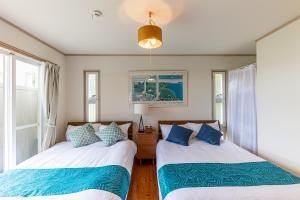恩納的住宿－Hermit Hills Okinawa  -SEVEN Hotels and Resorts-，带2扇窗户的客房内的2张床