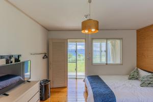 um quarto com uma cama e uma televisão de ecrã plano em Hermit Hills Okinawa  -SEVEN Hotels and Resorts- em Onna