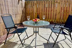 a table with a bowl of fruit and two wine glasses at The Smiddy in Inverness