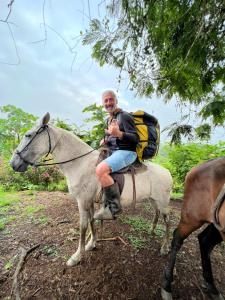 Ein Mann, der mit einem Rucksack auf einem Pferd sitzt. in der Unterkunft Oasis del Tortuguero in Cariari