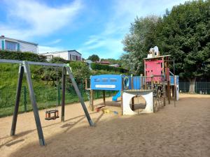 um parque infantil na areia ao lado de um edifício em Mobil home 3 chambres camping 4 étoiles em Saint-Martin-Plage