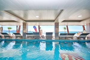 a swimming pool with chairs and the ocean in the background at Diamond Water Edge Resort in Boracay