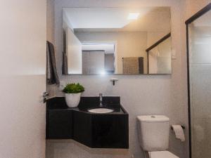La salle de bains est pourvue d'un lavabo, de toilettes et d'un miroir. dans l'établissement Flat em Lagoa Nova, Mobiliado e Aconchegante, à Natal