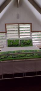 uma cama grande com lençóis verdes e almofadas em Gingerbread Cottage and Studio Fiji em Savusavu