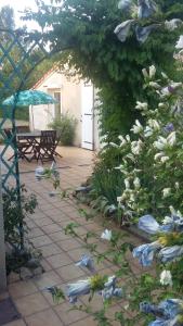 - une terrasse fleurie avec une table et un parasol dans l'établissement Pis-en-lits, à Viré