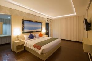 een hotelkamer met een groot bed en een televisie bij Grand Puri Saron Yogyakarta in Yogyakarta