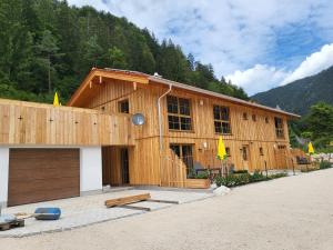a wooden building with a garage in front of a mountain at Nickis Bergcamp in Schneizlreuth