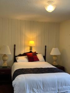 a bedroom with a large white bed with two lamps at Itascan Motel in Grand Rapids