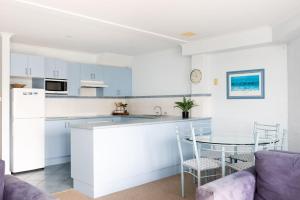 a kitchen with white cabinets and a table and chairs at Breakers 5 in Mollymook