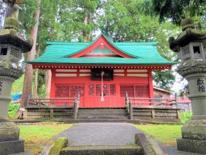 a red building with a green roof in a park at Tabist Shumisen-no-yado Tabataya Myoko-Togakushi in Myoko