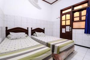 - 2 lits dans une chambre avec 2 fenêtres dans l'établissement Hotel Gajah Mada, à Sukodono