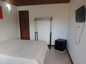 1 dormitorio con 1 cama y TV en la pared en Recanto do Jack, en Búzios