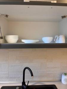 a kitchen counter with bowls and plates on a shelf at Barney Apartman in Sovata