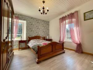 a bedroom with a wooden bed and pink curtains at Gîte chaleureux avec cheminée près du Puy-en-Velay, idéal pour familles et séjours professionnels - FR-1-582-349 in Saint-Germain-Laprade