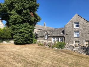 une ancienne maison en pierre avec un grand arbre en face dans l'établissement Sea Pink Cottage, à Swanage