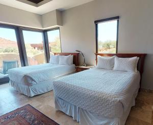 two beds in a room with large windows at Red Rock in St. George