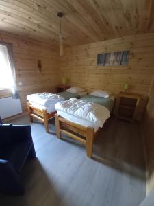 two beds in a room with wooden walls at Le chalet des Oisaï in Wibrin