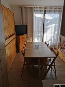 a living room with a wooden table and a television at Studio les fleury in Mieussy