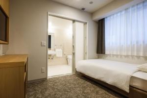 大阪Plum Hotel的一间卧室设有一张床和一个滑动玻璃门