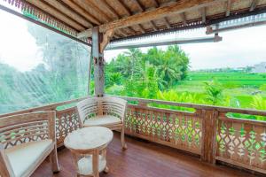 a balcony with chairs and a table and a view at Nauna Villa Ubud in Ubud