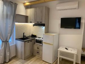 a small kitchen with a white refrigerator and a tv at il Centro in Ios Chora
