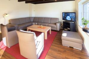 een woonkamer met een bank, een tafel en een tv bij Nordlicht in Norddeich