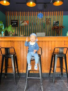 カットバ島にある2Stones Cát Bà Homestayの小さな子供がバーの椅子に座っている