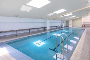 a large swimming pool with blue water in a building at Nesuto Canberra in Canberra