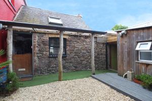 Elle offre une vue sur l'extérieur d'une maison en pierre dotée d'une terrasse. dans l'établissement The Bake House, à Llangennith