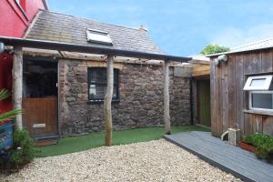 an external view of a stone house with a patio at The Bake House in Llangennith