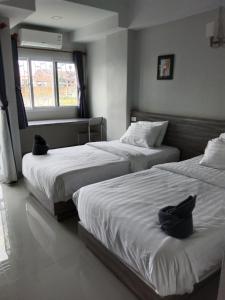 two beds in a hotel room with a window at The grace kok udom in Prachin Buri